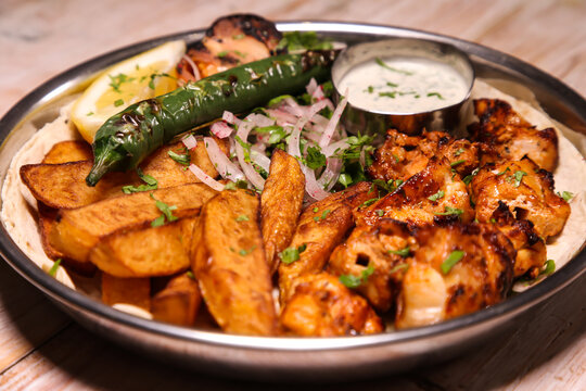 Shish tawook or tawooq with salad, wedges, lemon and dip served in dish isolated on background top view of arabic food