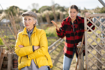 Two angry casual women neighbors of different ages arguing during the vegetable garden season on...