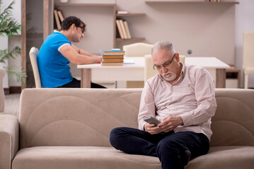 Fototapeta premium Young male student and his grandfather at home
