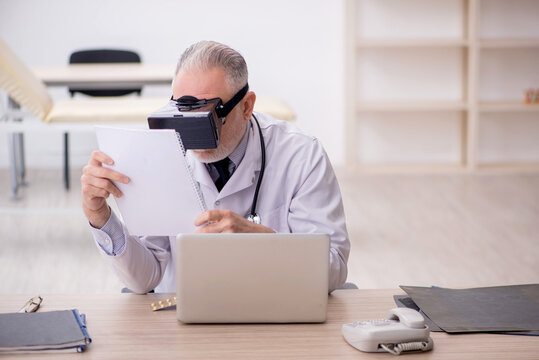 Old male doctor wearing virtual glasses in the clinic