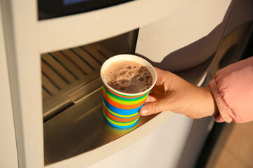 Woman taking paper cup with coffee from vending machine, closeup - obrazy, fototapety, plakaty
