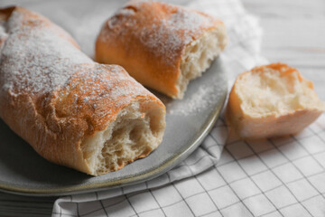 Fresh crispy ciabattas on white wooden table, closeup