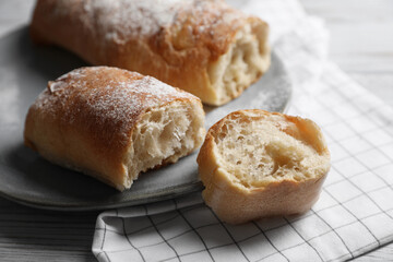 Fresh crispy ciabattas on white wooden table, closeup