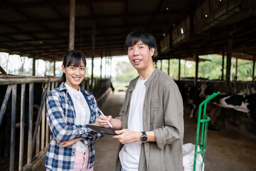 Portrait of two Asian veterinarians standing confidence while inspecting cows food at dairy farm, copy space.
