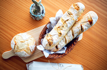 round homemade bread and baguette, on wooden board sprinkled with white flour