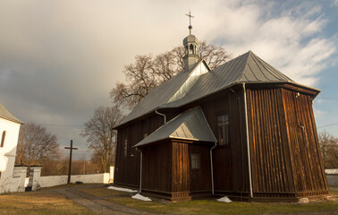 Drewniany , zabytkowy kościół pod wezwaniem Zaślubin Najświętszej Marii Panny . Kościół na tle ciemnego , pochmurnego nieba .
