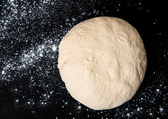 Raw dough for bread or pizza on a black background
