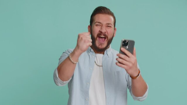 Happy excited joyful lebanese man in shirt use smartphone typing browsing shouting say wow yes found out great big win, good news, lottery goal achievemen, celebrating success, winning game