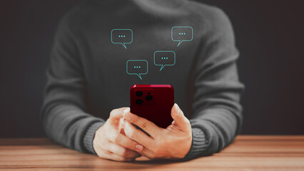 Social media application chat box on a mobile phone. Young man hand using a smartphone typing live chat chatting on application communication speech bubble digital web and social network concept.