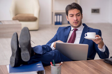 Young male employee drinking coffee during break