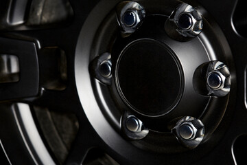 Close up of a Black Car Wheel Rim with Chrome Lug Nuts