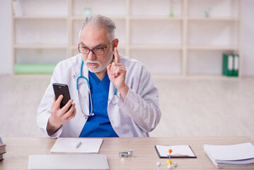 Old male doctor in telemedicine concept