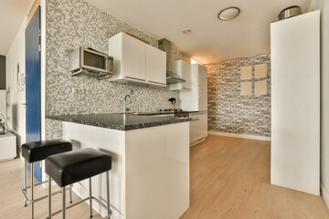 a kitchen area with white cabinets and black counter tops, two bar stools in the center of the room