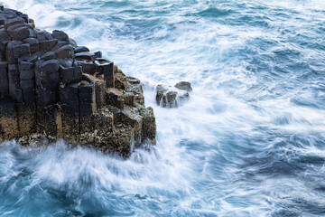 Waves breaking on rocks - long exposure photo of basalt columns on the coast