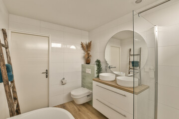 a modern bathroom with wood flooring and white tiles on the walls, including a large mirror over the bathtub
