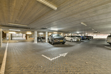 an underground parking area with cars parked in the garages and people walking on the sidewalk to...