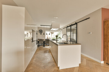 a kitchen and dining area in a house with wood flooring, white walls and an open door leading to the living room