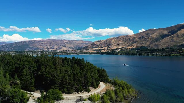 Aerial footage of boat sailing on Wanaka Lake with forest on shore