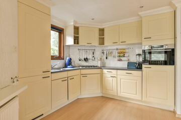 a kitchen with white cabinets and light wood flooring in the middle of the room, looking into the dining area
