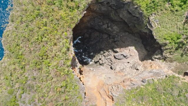 Cave in national park aerial drone rising, natural rock formation by the sea