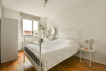 a bedroom with white walls and wood flooring the room has a bed in it is next to a window