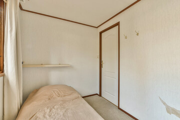 a bed in a room with white walls and wood trim on the wall behind it is an open door that leads to a window