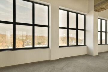 an empty room with large windows and no one person standing in the window looking out to the city outside,