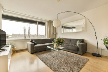 a living room with a couch, coffee table, tv and large window looking out onto the cityscape
