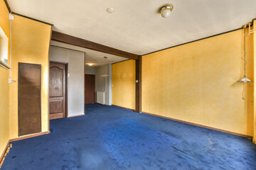 an empty room with yellow walls and blue carpet in the middle of the room, there is a door leading to another room
