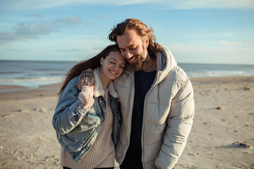 Young adult couple walking on a beach during cold weather