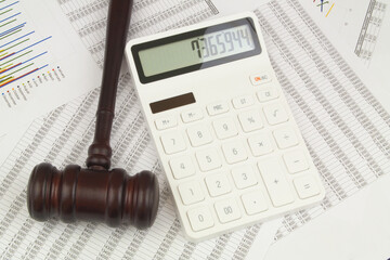 Calculator and wooden judge gavel on financial documents. Fraud and arbitrage concept.	