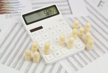 Statistics and people concept. Wooden people figures going through calculator on documents...