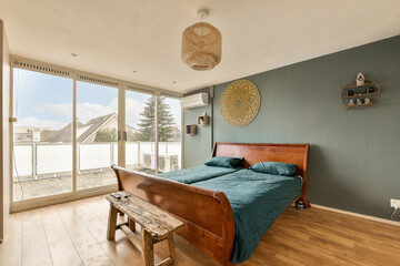 a bedroom with blue walls and wood flooring, including a bed in the fore - windowed room to the outside