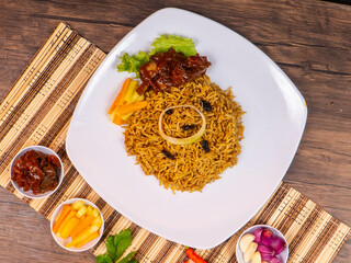 Kebuli Kambing Rice with Sliced ​​Mutton and Pickles, on a white bowl against a wooden background
