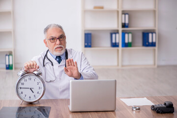 Old male doctor in time management concept