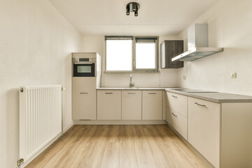a kitchen with white cabinets and wood flooring in the middle of the room, looking into the dining area