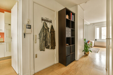 the inside of a house with wood floors and white walls, there is a coat rack hanging on the door