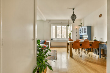 a kitchen and dining area in a room with hardwood floors, white walls, wooden flooring and an open door leading to the