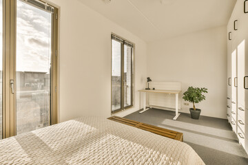 Fototapeta na wymiar a bedroom with a bed, desk and large window looking out onto the cityscapearrons com