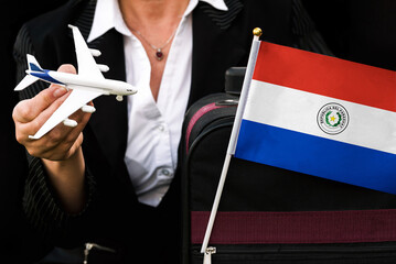 business woman holds toy plane travel bag and flag of Paraguay
