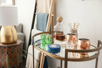 styled bar cart in apartment with decanter, moscow mule copper mugs, green glasses and coasters