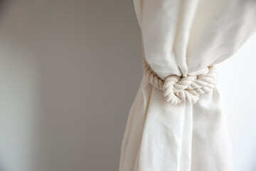 white rope curtain pull tied around white linen curtain, room for copy