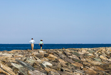 Shot of the couple walking on the rocks by the beach. Concept