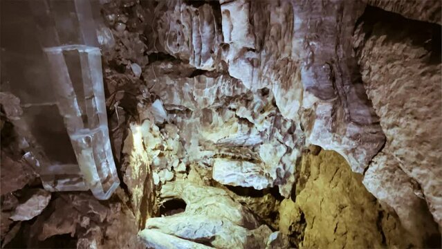 Excursion to the dark ice cave in winter. Underground large stone cave. Tourism in Russia. Dimly lit walls in an ice cave. Mammoth sculpture in Kungur ice cave, Russia. 4K