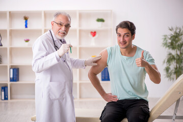 Young male patient visiting old male doctor in vaccination conce