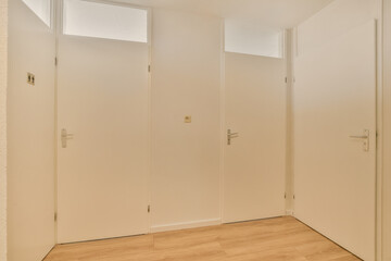 an empty room with wooden floors and white walls, two closed doors on either side of each door are open