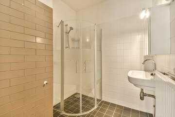 a bathroom with a sink and shower stall in the corner next to it is a tiled wall, white tiles on the floor