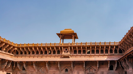 Details of the architecture of the Jahangir Mahal Palace. The upper part of the building with galleries, arches, carved decorations. On the roof there is a pavilion with a dome, a lattice fence.