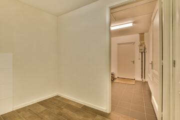 an empty room with white walls and brown tile on the floor there is a door in the corner that leads to another room
