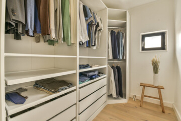 the inside of a walk - in closet with clothes hanging on shelves, and wooden flooring boards around it